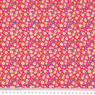 Ditsy flowers and sky blue green vines on a dusk pink polycotton fabric with a cm ruler