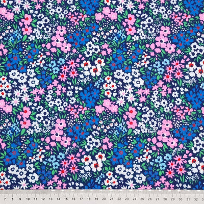 Ditsy flowers in pinks and blues are printed on a navy polycotton fabric with a cm ruler