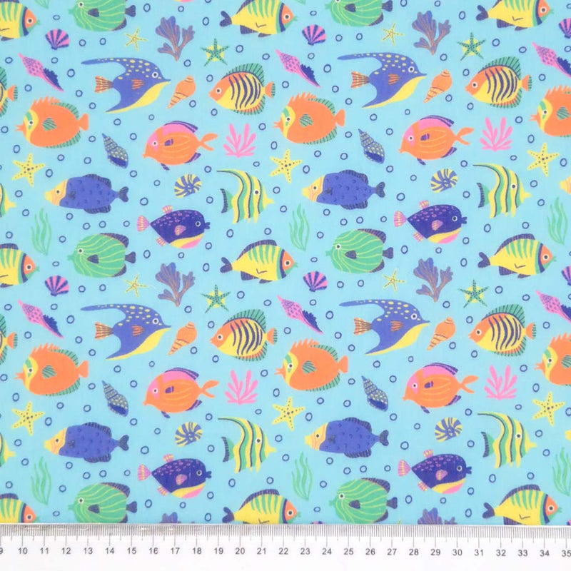 Tropical fish printed on a sky blue polycotton fabric with a cm ruler