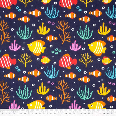 Brightly coloured fish are printed on a navy polycotton fabric with a cm ruler