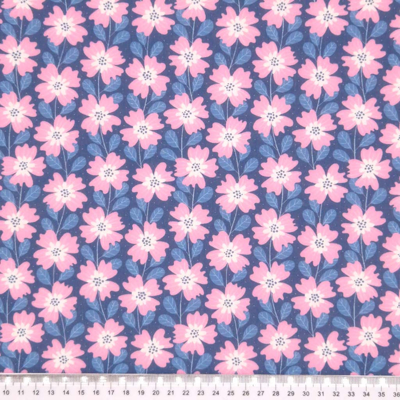 Baby pink and white flowers strung together by dusk blue vines on a night-sky blue polycotton fabric. with a cm ruler