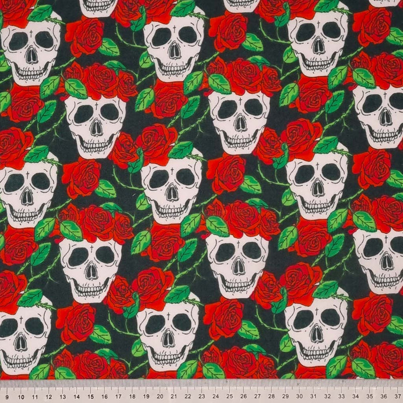 Skulls and red roses are printed on a black polycotton fabric with a cm ruler