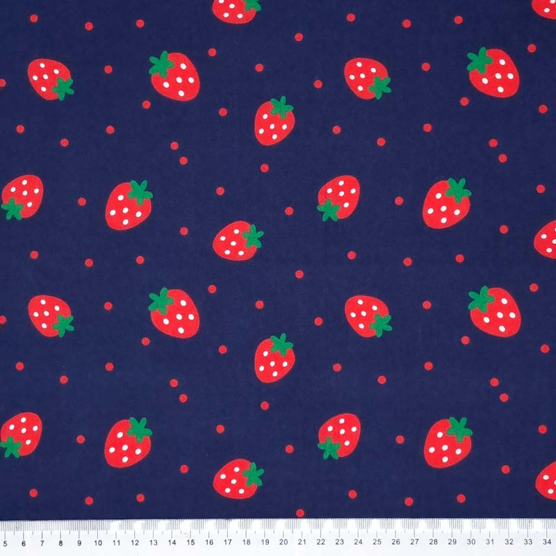 Spotty red strawberries with green stalks are printed on a navy blue polycotton fabric with scattered red spots and a cm ruler