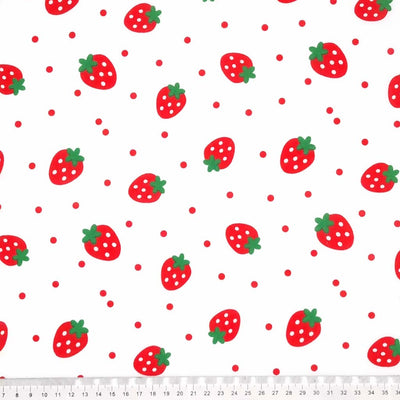 Spotty red strawberries with green stalks are printed on a white polycotton fabric with scattered red spots. with a cm ruler
