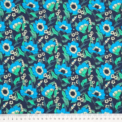 Blooming turquoise flowers are printed on a navy polycotton fabric with a cm ruler