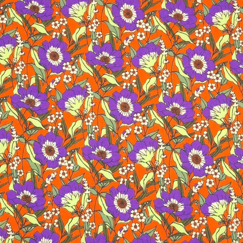 Blooming purple flowers are printed on an orange polycotton fabric