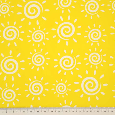 White swirly suns are printed on a yellow polycotton fabric with a cm ruler