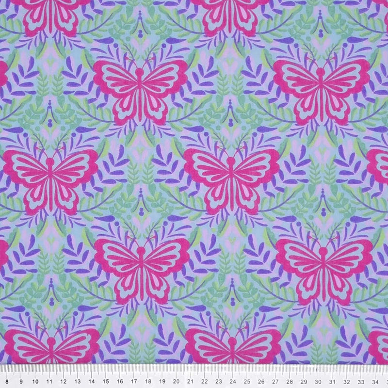 Large butterflies in cerise are printed on a lilac and sky blue coloured polycotton fabric with a cm ruler