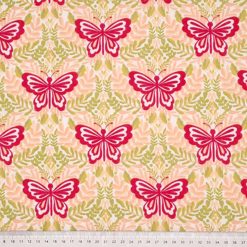 Large magenta butterflies printed on a peach and green polycotton fabric with a cm ruler