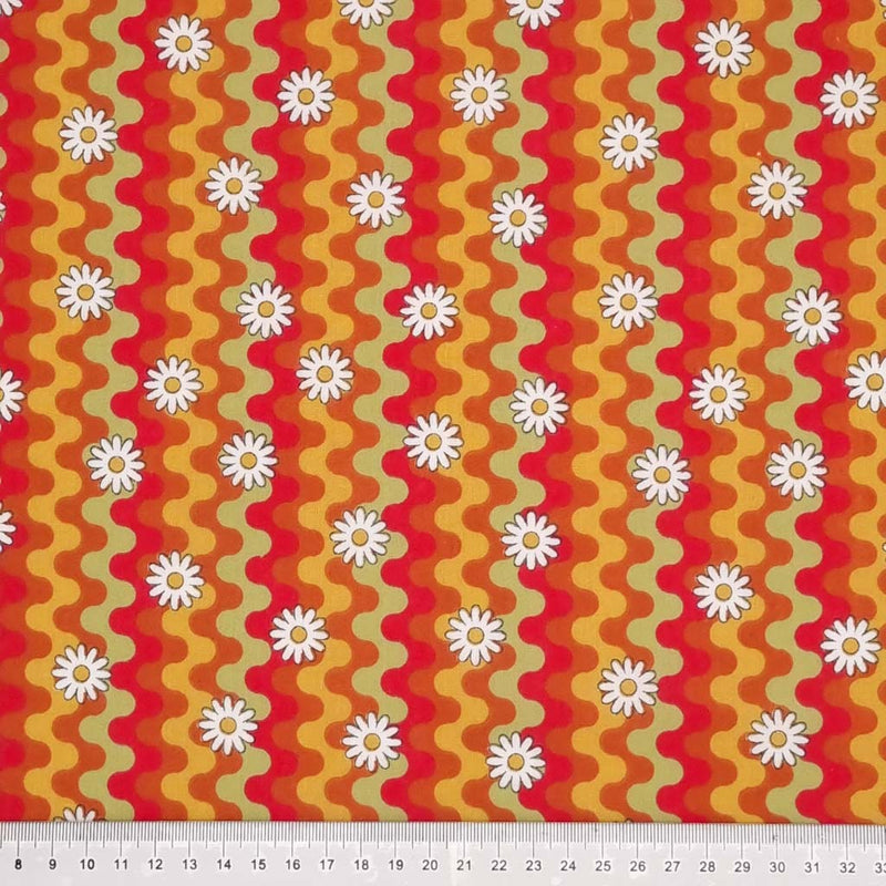 Daisies are printed with a retro squiggle pattern in vibrant reds and green colours on a polycotton fabric with a cm ruler