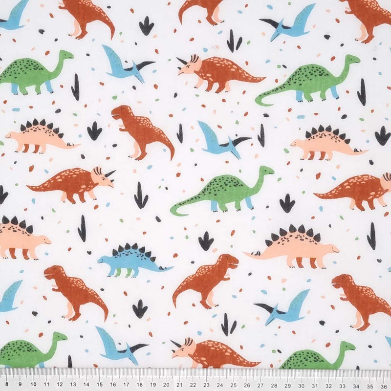 Green and brown dinosaurs printed on a white polycotton fabric with a cm ruler