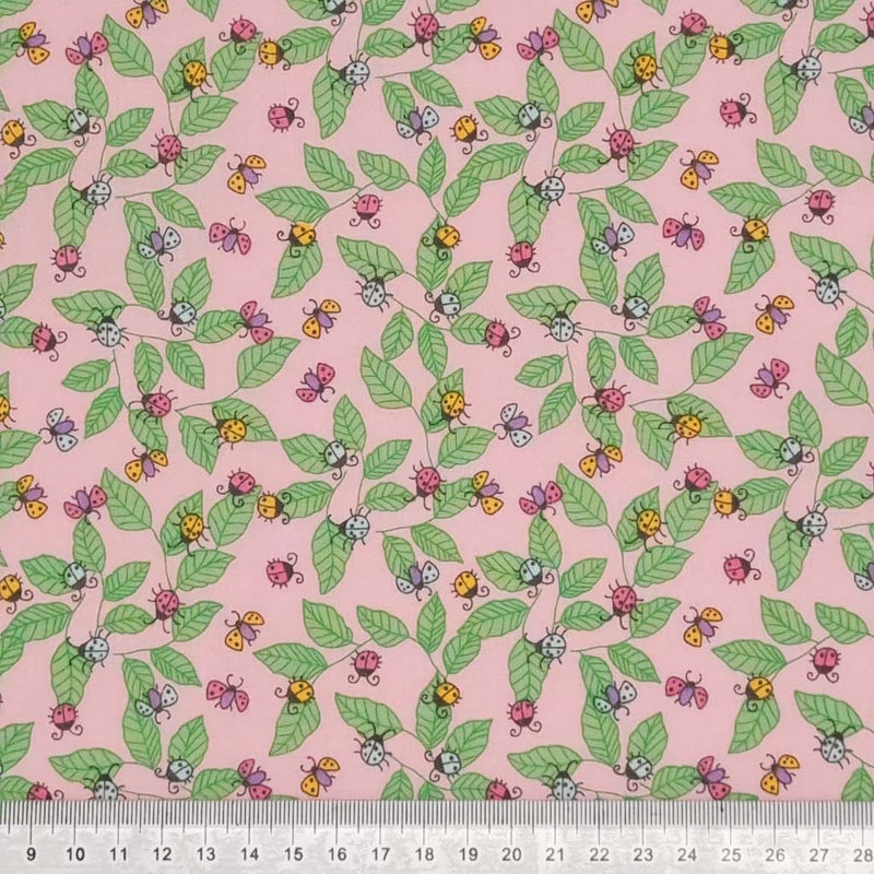 Pink and yellow ladybirds printed on a pink polycotton fabric with a cm ruler