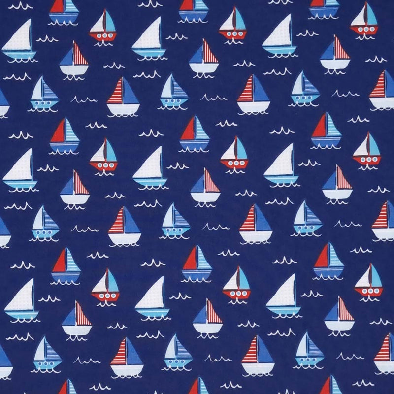 Red, white and blue sailing boats printed on a navy polycotton fabric