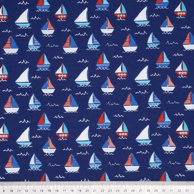 Red, white and blue sailing boats printed on a navy polycotton fabric with a cm ruler