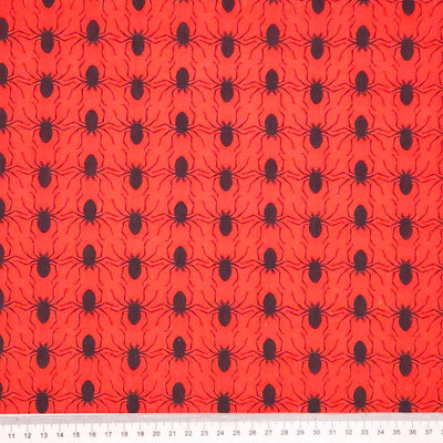 Red halloween polycotton fabric with black spider pattern and a ruler at the bottom for scale.