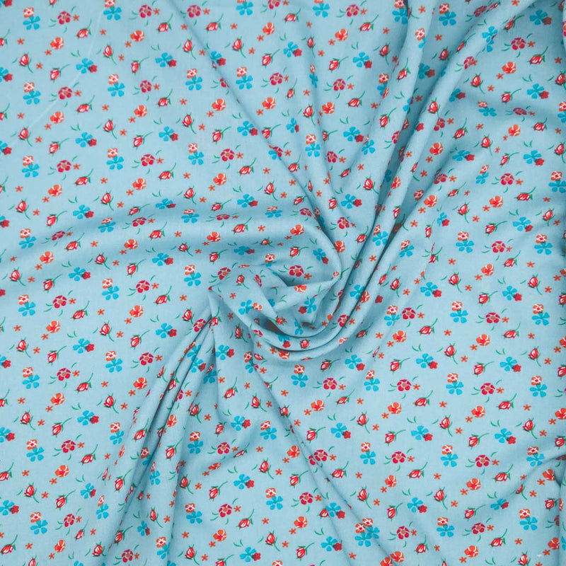 Floral patterned fabric with red and blue flowers on a light blue viscose fabric