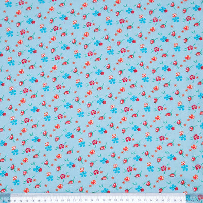 Floral patterned fabric with red and blue flowers on a light blue viscose fabric with a ruler