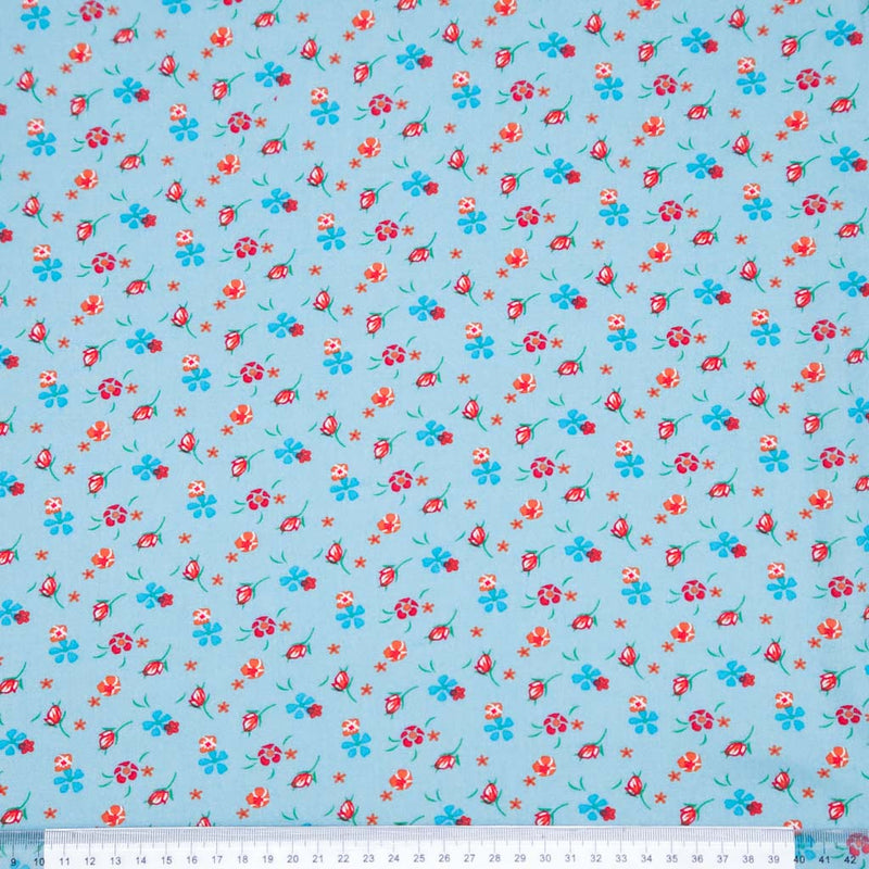 Floral patterned fabric with red and blue flowers on a light blue viscose fabric with a ruler