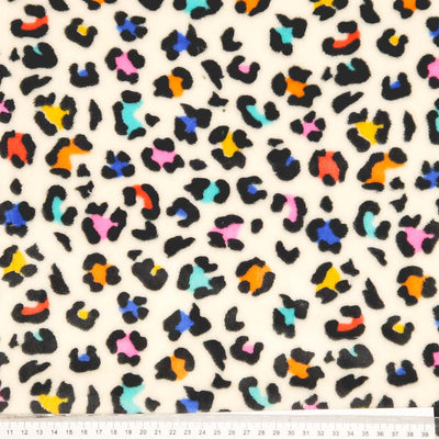 Colorful leopard print pattern on a beige fleece fabric with a ruler at the bottom.