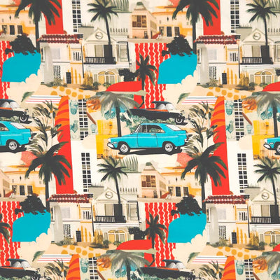 A cool graphic design featuring a vintage blue car traveling amongst palm trees, holiday houses and bold areas of stripy red and blue patchwork, digitally printed on a cotton jersey fabric