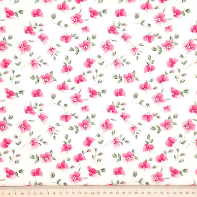 Pattern of small pink flowers with green leaves on a white background printed on a cotton poplin fabric with a cm ruler