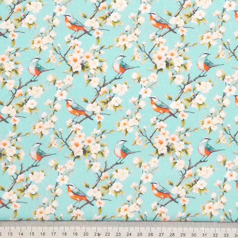 Pattern of birds and flowers on a turquoise background printed on cotton poplin fabric with a cm ruler