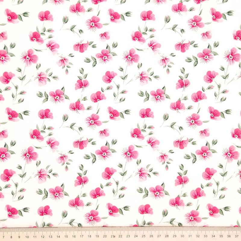 Pattern of small pink flowers with green leaves on a white background printed on a cotton poplin fabric with a cm ruler