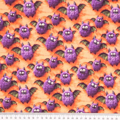 Pattern of purple bats on an orange cotton fabric with a cm ruler