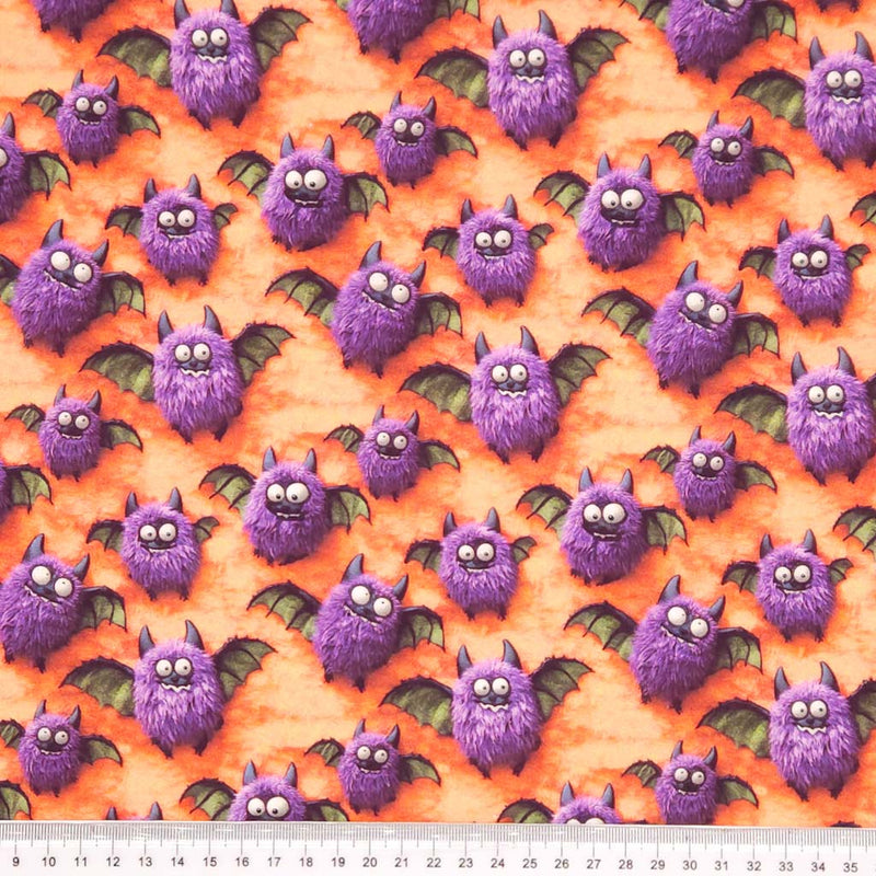 Pattern of purple bats on an orange cotton fabric with a cm ruler