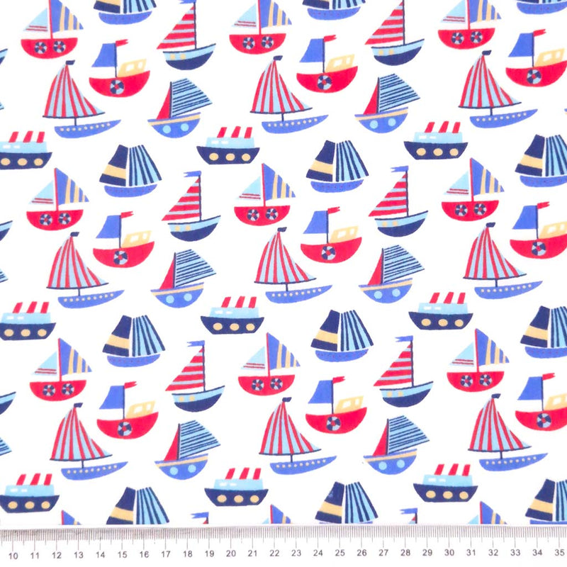 Red and blue sailing boats printed on a white polycotton fabric with a cm ruler