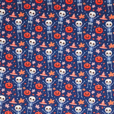 Pattern of skeletons, pumpkins, and leaves on an indigo halloween polycotton fabric