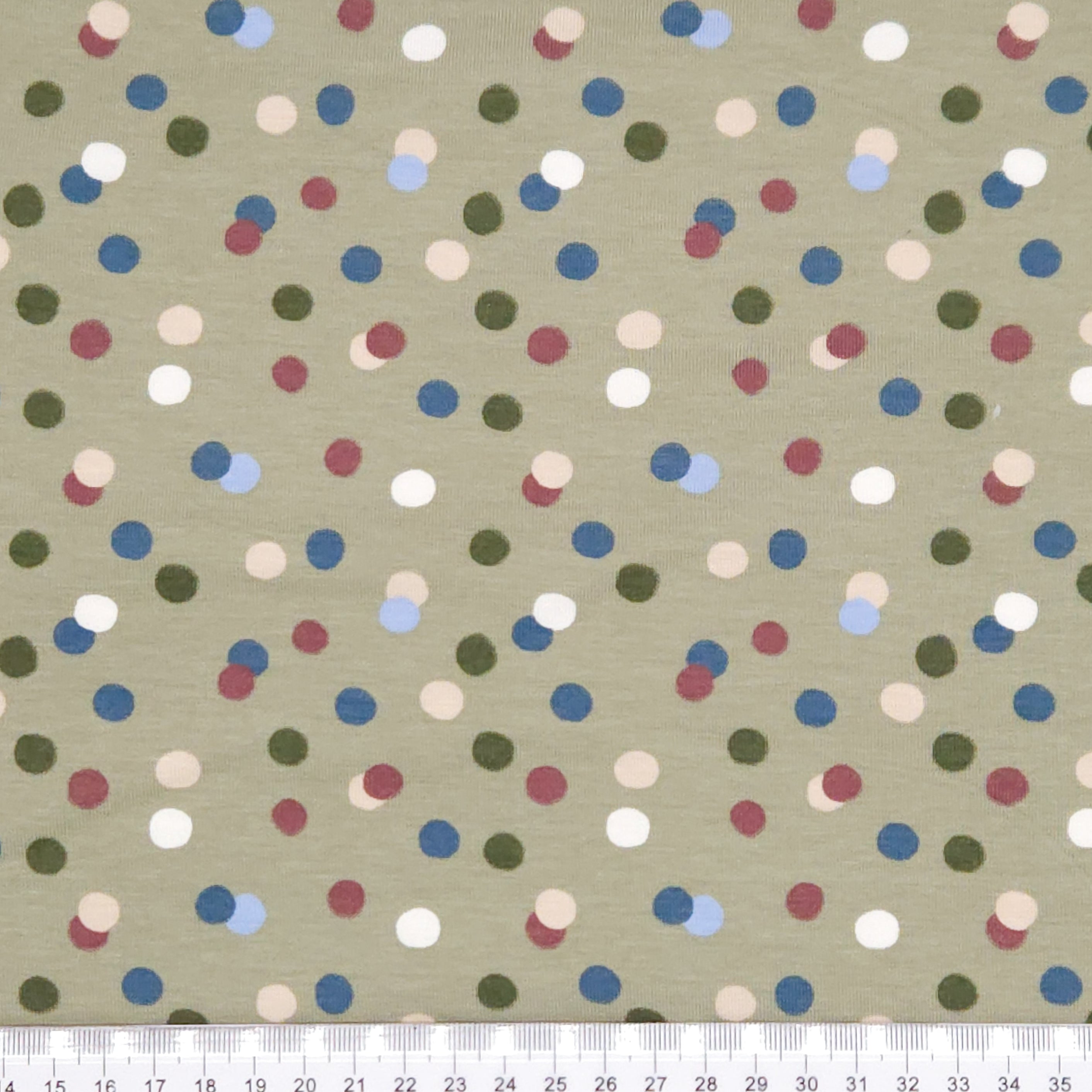 Dots printed on an olive green cotton jersey fabric with a cm ruler