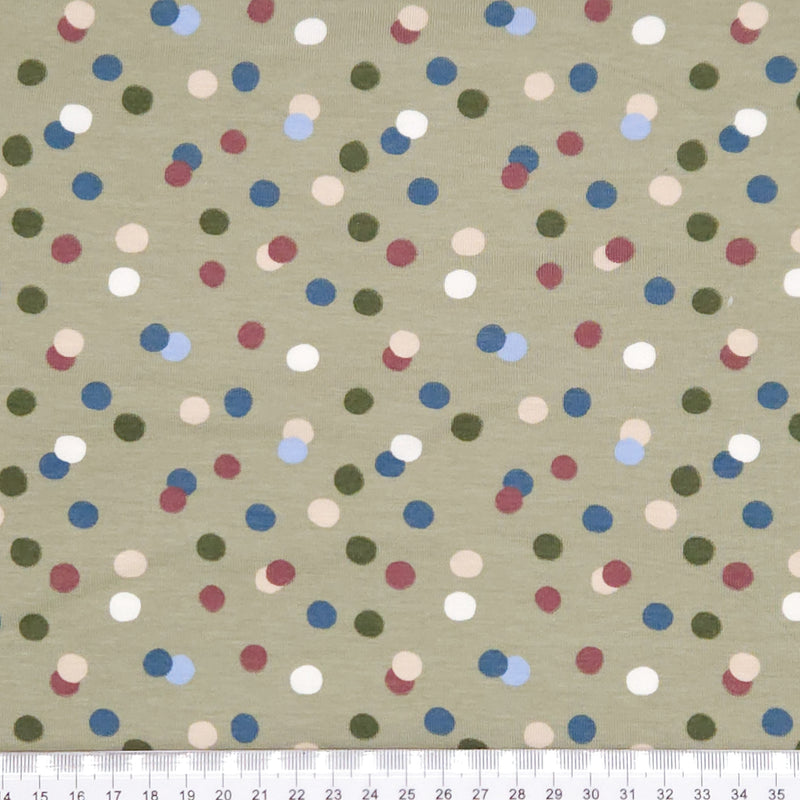 Dots printed on an olive green cotton jersey fabric with a cm ruler