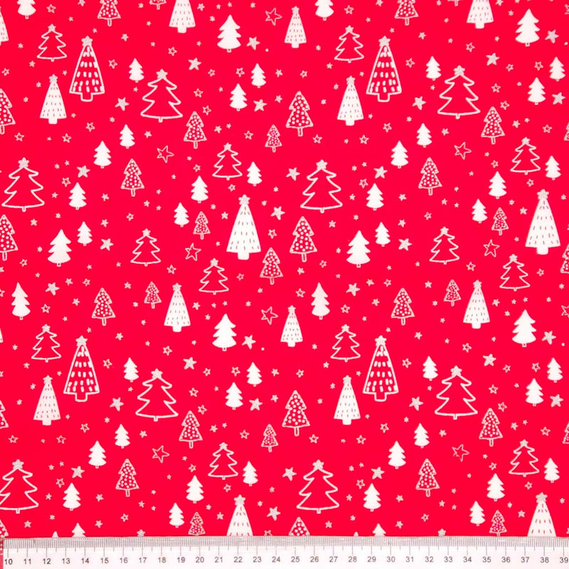 Pattern of white Christmas trees and stars on a red cotton fabric with a ruler