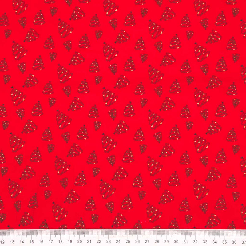 Red cotton fabric with small black and white christmas trees with a ruler