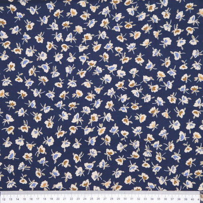 Floral patterned fabric with small flowers on a blue background, measured against a ruler.