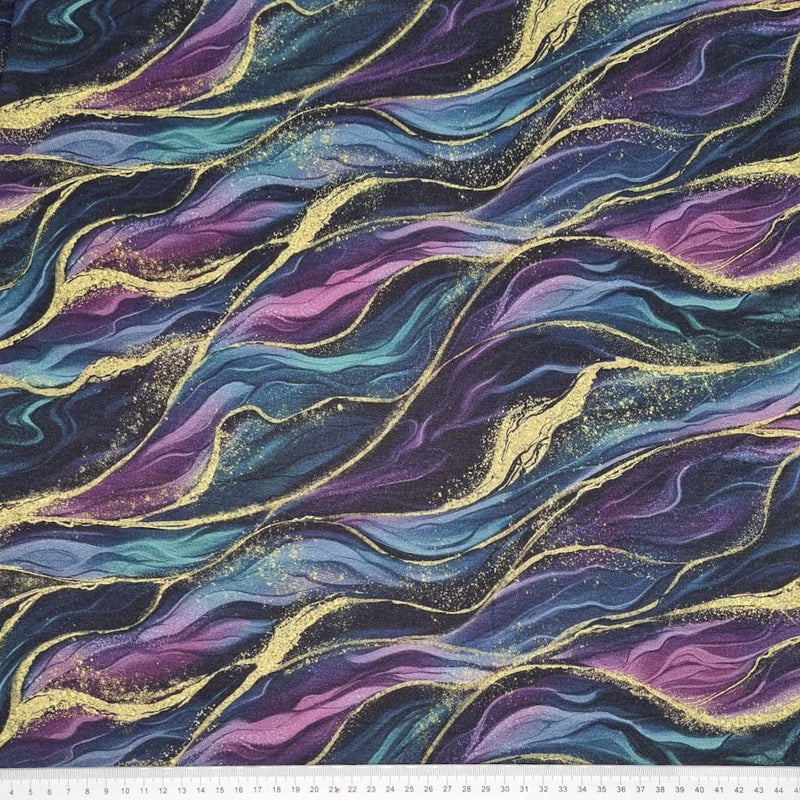 Waves in gold, purple and teal are printed on a jersey fabric with a cm ruler
