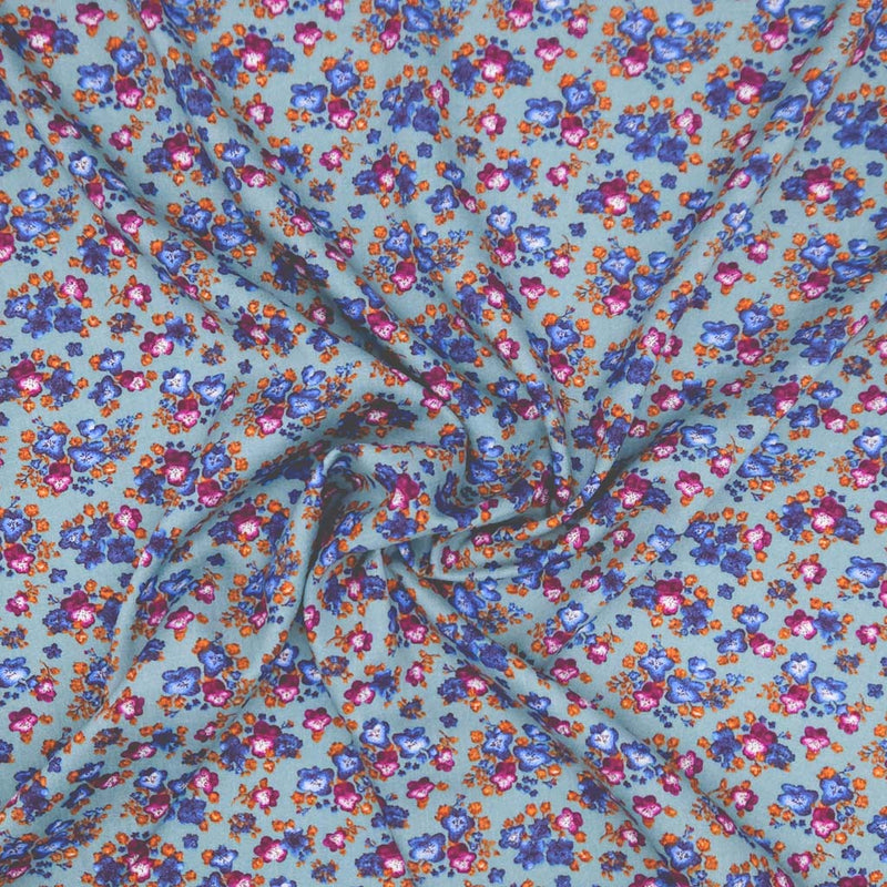Floral fabric pattern with small flowers in blue, pink, and orange on a teal viscose fabric