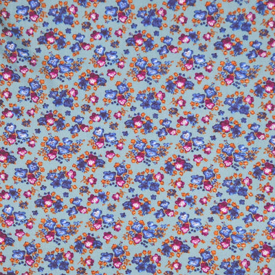 Floral fabric pattern with small flowers in blue, pink, and orange on a teal viscose fabric