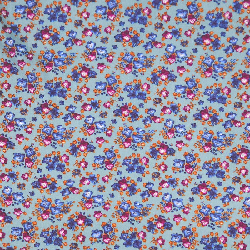 Floral fabric pattern with small flowers in blue, pink, and orange on a teal viscose fabric