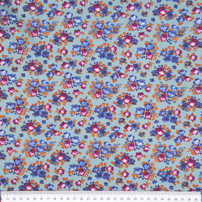 Floral fabric pattern with small flowers in blue, pink, and orange on a teal viscose fabric with a ruler
