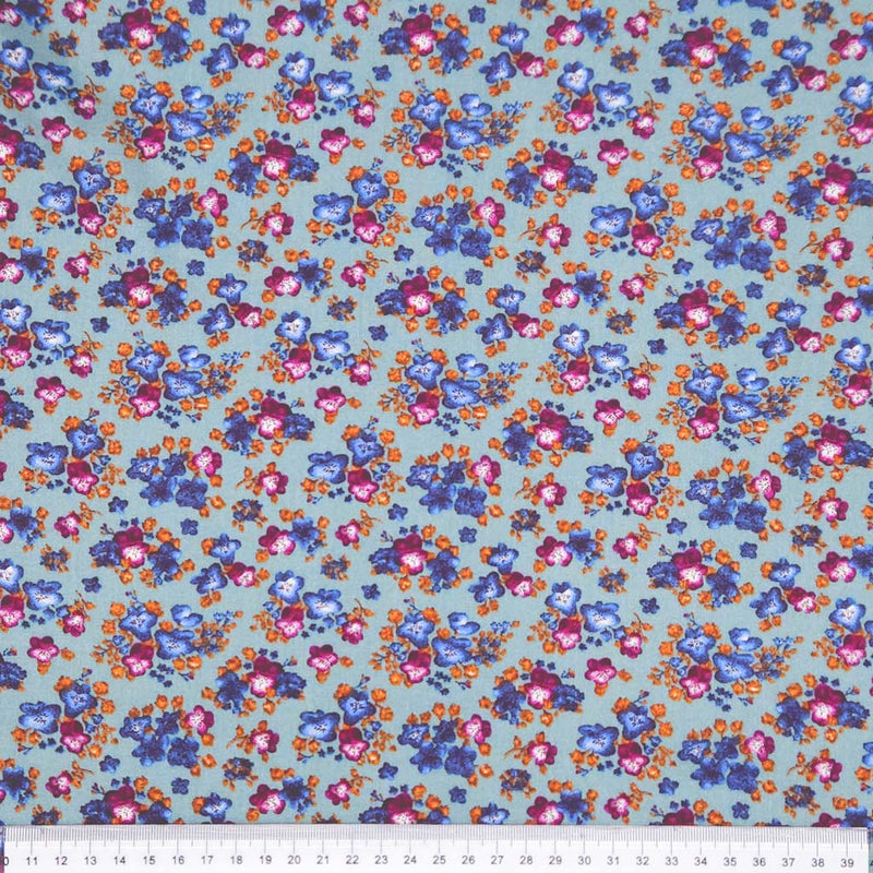 Floral fabric pattern with small flowers in blue, pink, and orange on a teal viscose fabric with a ruler