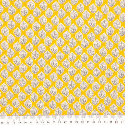 Leaves printed on a yellow viscose dressmaking fabric with a cm ruler