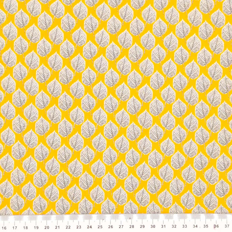 Leaves printed on a yellow viscose dressmaking fabric with a cm ruler