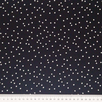 Small scattered white spots printed on black viscose fabric with a cm ruler