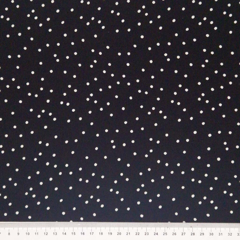 Small scattered white spots printed on black viscose fabric with a cm ruler