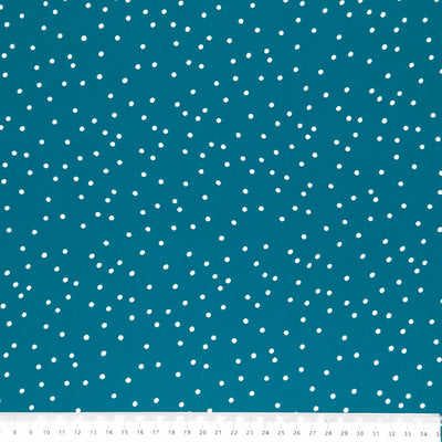 Small scattered white spots printed on teal viscose fabric with a cm ruler