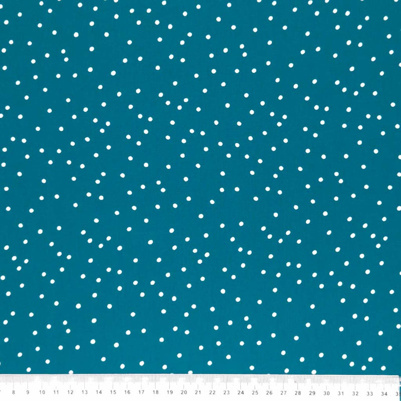 Small scattered white spots printed on teal viscose fabric with a cm ruler