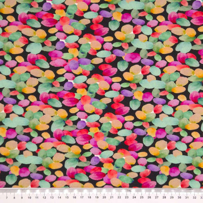 Colourful spots printed on a black viscose jersey fabric with a cm ruler