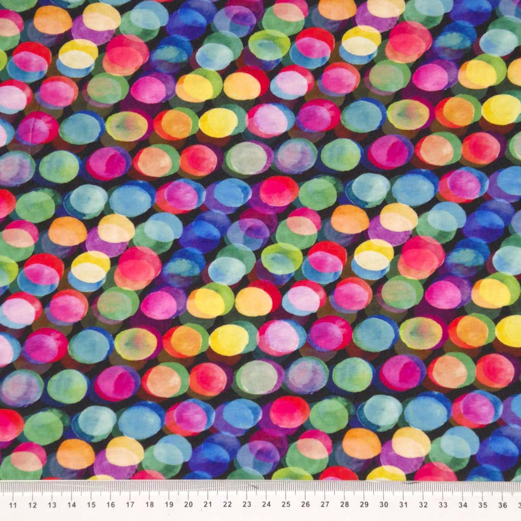 Vibrantly coloured spots printed on a black viscose jersey fabric with a cm ruler